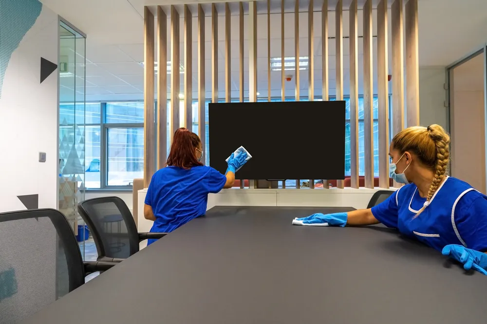 Cleaners wiping a conference table in an office