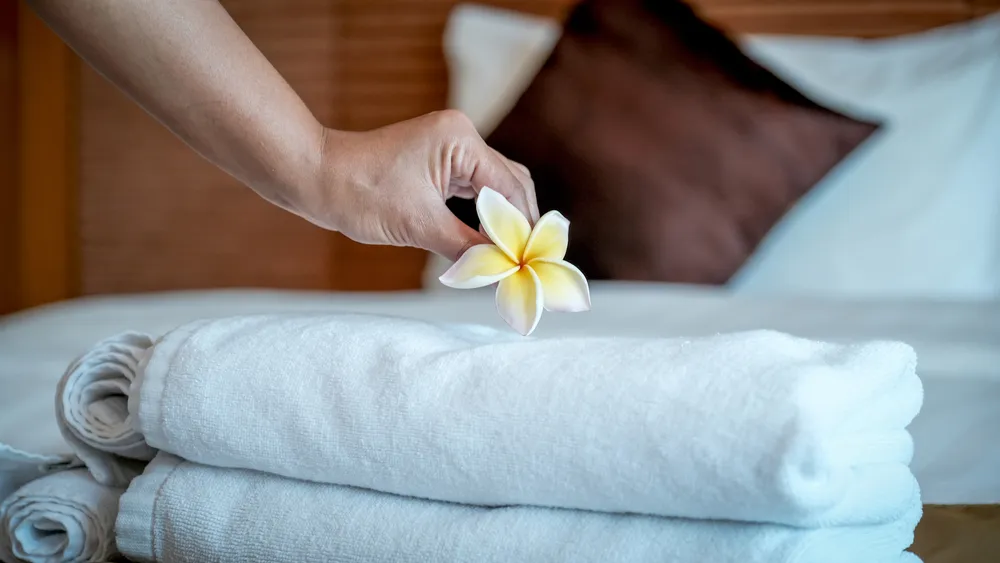 Fresh towels being arranged on a guest-room bed